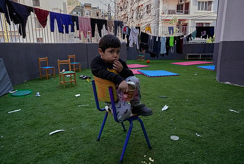 A displaced boy who fled Israeli strikes in southern Lebanon with his family sits on the backyard school that turned into a shelter in Beirut, Lebanon, Tuesday, March 10, 2026. 