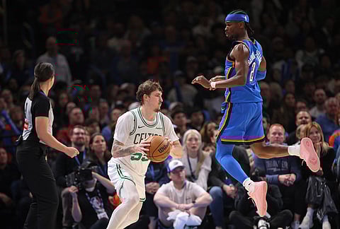 Boston Celtics guard Baylor Scheierman, center, handles the ball as Oklahoma City Thunder guard Shai Gilgeous-Alexander (2) defends during the first half of an NBA basketball game in Oklahoma City. 