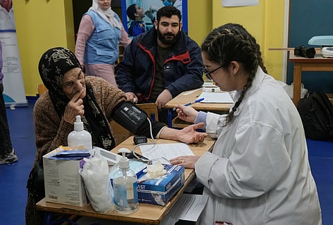 A nurse, right, measures the blood pressure of a woman who fled Israeli airstrikes in Dahiyeh, Beirut's southern suburbs, at a school turned into a shelter in Beirut, Lebanon, Saturday, March 7, 2026. 