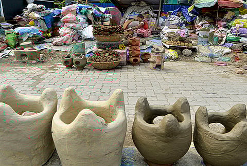 A woman displays earthen clay stoves and cow dung cakes used for cooking and religious rituals, at a stall in Siliguri, West Bengal.