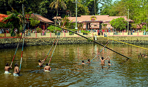 People perform 'Kodimaram' fixing ritual at a pond in the 'Irumkulangara Devi Temple' during the 'Thrikkodiyettu' festival, in Thiruvananthapuram, Kerala.