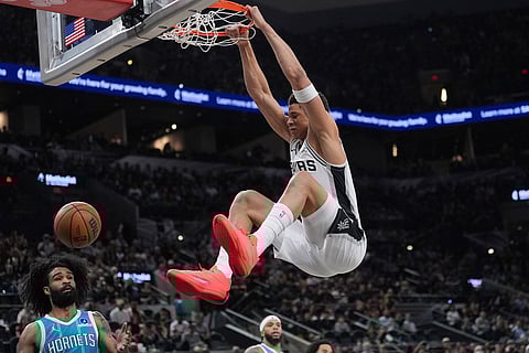 San Antonio Spurs forward Carter Bryant (11) scores over Charlotte Hornets guard Coby White (3) during the first half of an NBA basketball game in San Antonio.