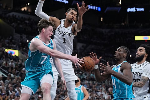 Charlotte Hornets guard Kon Knueppel (7) is pressured by San Antonio Spurs forward Victor Wembanyama (1) as he passes to teammate guard Sion James (4) during the second half of an NBA basketball game in San Antonio.