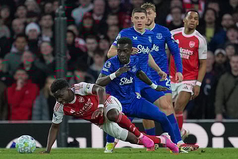 Arsenal's Bukayo Saka, left, and Everton's Idrissa Gueye fight for the ball during the English Premier League soccer match between Arsenal and Everton in London, England.