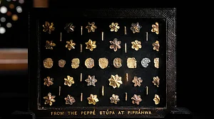 Photo: Vikram Sharma : A few of the relics that were taken out of the country by Peppe and repatriated in 2025.
In 1898, William Claxton Peppé discovered the Piprahwa gem relics, which led to 349 gem relics being placed under his custody. A significant portion of these relics became part of the Imperial Museum in Calcutta, now known as the Indian Museum in Kolkata. The museum classified these relics as ‘AA’ antiquities, which prohibited their sale and restricted their movement. However, they are now displayed in this magnificent exhibition for the first time and reunited with the repatriated gem relics which were once taken away from India by the Peppé family. These gems, made from semiprecious stones, pearls, and beads, are shaped into emblems such as the tri-ratna, bird, leaf, and lotus motifs. Alongside these gems are numerous pieces of gold and silver leaf, some of which are impressed with crosses, lions, and early Buddhist symbols. Among the unique pieces is a group of tiny ornaments referred to as “star-shaped flowers” by Harry Falk. These jewels were carved from small, flat stone cones, hollowed at the centre and shaped into six or more petals by meticulously sawing the stone between them. This process required great skill and precision. Each ornament has a central perforation, indicating that they were initially strung, possibly as part of a necklace, garland, or decorative textile. A faint circular mark where the petals meet suggests that they were shaped using a thread saw, a delicate ancient tool.