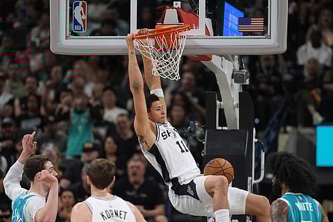 San Antonio Spurs forward Carter Bryant (11) scores past Charlotte Hornets center Ryan Kalkbrenner, left, during the second half of an NBA basketball game in San Antonio.