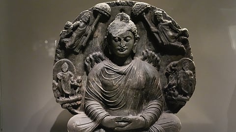 The Miracle of Śrāvastī 

 Time Period
C. 2nd Century CE, Kushana, Gandhara

Location found
 Kabul (North-West part of Undivided India)

The Miracle of Śrāvastī from the Gandhara School portrays the Buddha performing the Twin Miracle, emitting flames and water from his body while multiplying his image to manifest his spiritual supremacy. Carved in gray schist, the Buddha sits in dhyana mudra, surrounded by smaller Buddhas and celestial figures. Flames rising from his back symbolize enlightenment and transcendence. This relief exemplifies Gandharan artistry, merging Greco-Roman naturalism with Buddhist symbolism, expressing the Buddha’s divine power and serene, enlightened presence.
