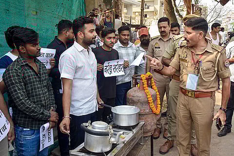 A police official speaks to NSUI students as they hold a protest, wherein they demonstrate making tea by extracting gas from a drain amid "LPG crisis", in Varanasi,.