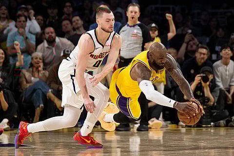 Los Angeles Lakers forward LeBron James, right, dives for the loose ball past Denver Nuggets guard Christian Braun during the second half of an NBA basketball game in Los Angeles.
