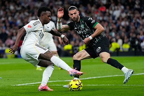 Real Madrid's Vinicius Junior, left, is challenged by Elche's Leo Petrot during a Spanish La Liga soccer match between Real Madrid and Elche CF, in Madrid.