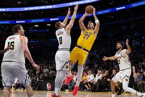 Los Angeles Lakers guard Luka Doncic (77) shoots as Denver Nuggets guard Christian Braun (0) defends during the second half of an NBA basketball game in Los Angeles.