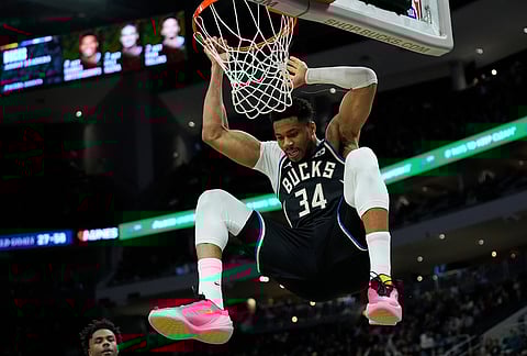 Milwaukee Bucks' Giannis Antetokounmpo hangs on the rim after dunking during the second half of an NBA basketball game against the Indiana Pacers, in Milwaukee. 
