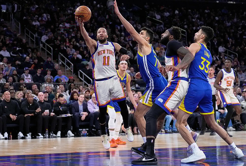 New York Knicks' Jalen Brunson (11), left, drives to the basket past Golden State Warriors defenders during the second half of an NBA basketball game in New York.  - | Photo: AP/Seth Wenig
