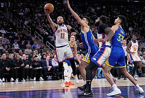 | Photo: AP/Seth Wenig : New York Knicks' Jalen Brunson (11), left, drives to the basket past Golden State Warriors defenders during the second half of an NBA basketball game in New York.