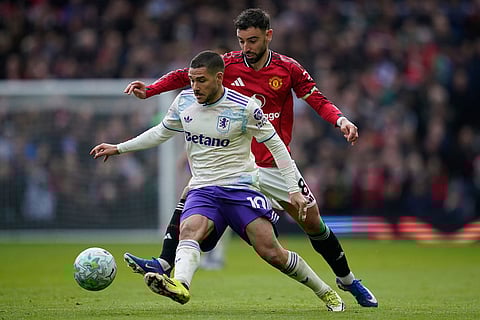 Aston Villa's Emiliano Buendia, front, and Manchester United's Bruno Fernandes fight for the ball during the Premier League soccer match between Manchester United and Aston Villa in Manchester, England.