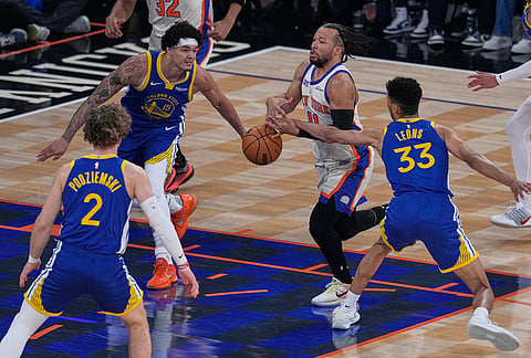 New York Knicks' Jalen Brunson, second from right, loses the ball as he drives to the basket during the first half of an NBA basketball game against the Golden State Warriors in New York.
