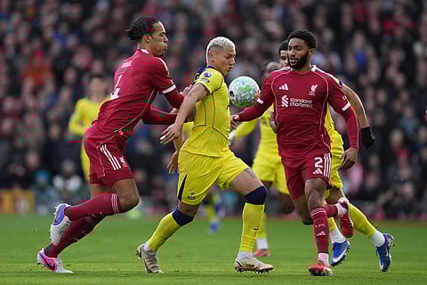 Liverpool's Virgil van Dijk, left, and Tottenham's Richarlison fight for the ball during the Premier League soccer match between Liverpool and Tottenham in Liverpool, England.
