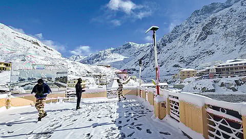 Security personnel walk through snow-covered area, in Badrinath, Chamoli district. The higher reaches of Himachal Pradesh received a fresh spell of snow on Monday morning. 