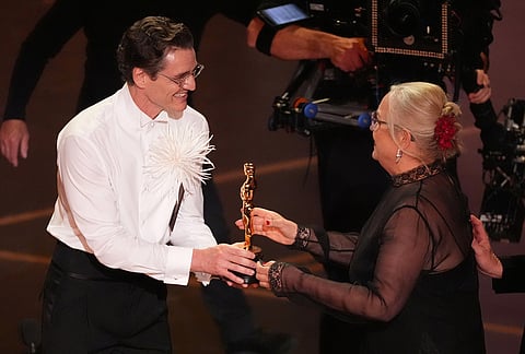 Pedro Pascal, left, presents the award for best production design to Tamara Deverell for "Frankenstein" during the Oscars at the Dolby Theatre in Los Angeles. 