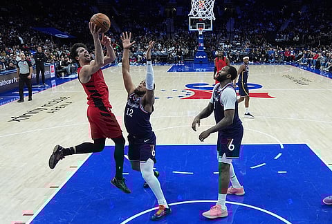 Portland Trail Blazers' Deni Avdija, left, goes up to shoot against Philadelphia 76ers' Trendon Watford (12) and Andre Drummond during the second half of an NBA basketball game in Philadelphia.