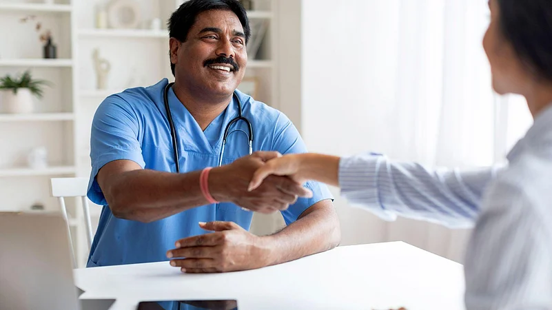 Smiling male doctor shaking hands with a patient