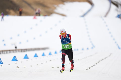 Wang Chenyang, of China, crosses the finish line in the cross country skiing men's 10Km interval start classic standing final at the 2026 Winter Paralympics, in Tesero, Italy.