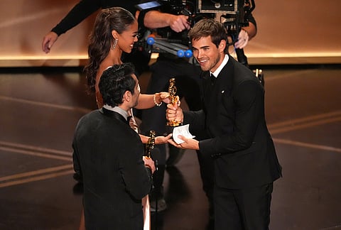 Kumail Nanjiani, left, presents the award for best live action short film to Sam A. Davis for "The Singers" during the Oscars at the Dolby Theatre in Los Angeles.