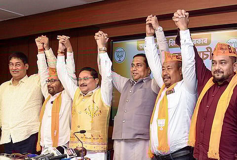 Assam BJP President Dilip Saikia joins hands with newly joined party leader Bhupen Roy and other leaders during a press conference, in Guwahati.