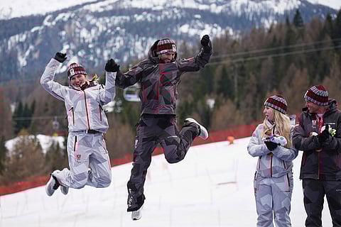 Gold medalists Veronika Aigner, of Austria, left, and her guide Eric Digruber celebrate on the podium of the alpine skiing women's giant slalom vision impaired, watched by bronze medalists Elina Stary, of Austria, and her guide Stefan Winter, right, at the 2026 Winter Paralympics, in Cortina d'Ampezzo, Italy.