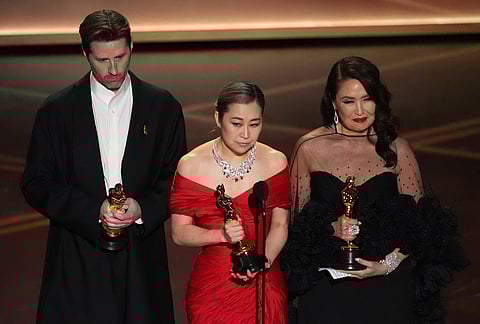Chris Appelhans, from left, Maggie Kang, and Michelle L.M. Wong accept the award for animated feature film for "K-pop Demon Hunters" during the Oscars at the Dolby Theatre in Los Angeles.