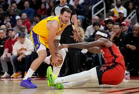 Houston Rockets' Tari Eason, right, falls while guarding Los Angeles Lakers' Luka Doncic during the first half of an NBA basketball game in Houston. 