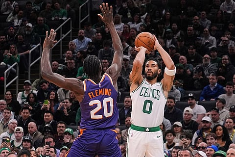 Boston Celtics forward Jayson Tatum (0) takes a 3-point shot over Phoenix Suns forward Rasheer Fleming (20) during the first half of an NBA basketball game in Boston.