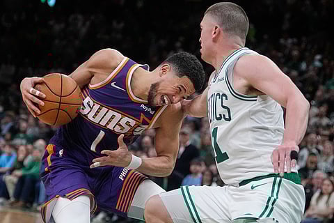Phoenix Suns guard Devin Booker (1) is fouled by Boston Celtics guard Payton Pritchard during the second half of an NBA basketball game in Boston.