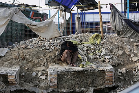 A man sits beside the site of a late-Monday airstrike at a drug rehabilitation hospital in Kabul, Afghanistan.