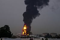 | Photo: AP : Fire and plumes of smoke rises after a drone struck a fuel tank forcing the temporary suspension of flights. near Dubai International Airport, in United Arab Emirates, early Monday, March 16, 2026. 
