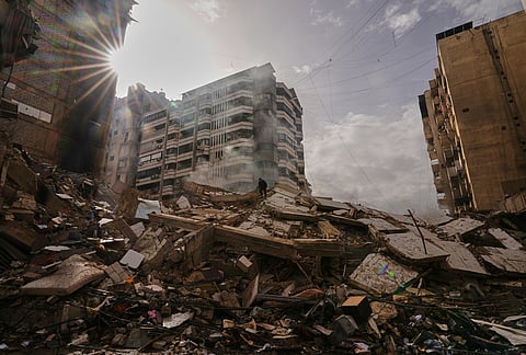 A man stands atop the rubble as smoke rises from a building destroyed in an Israeli airstrike in Dahiyeh, Beirut's southern suburbs, Lebanon, Saturday, March 14, 2026. 

