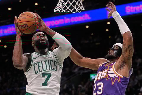 Boston Celtics guard Jaylen Brown (7) is fouled by Phoenix Suns guard Jordan Goodwin (23) on a drive to the basket during the first half of an NBA basketball game in Boston.