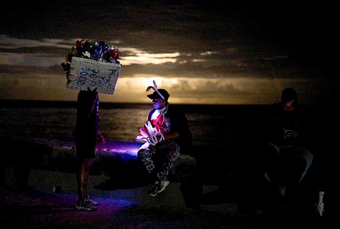 Street vendors chat on the Malecón during a blackout in Havana, Monday, March 16, 2026. 