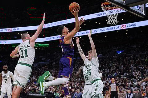 Phoenix Suns guard Devin Booker (1) drives to the basket against Boston Celtics guard Baylor Scheierman (55) during the second half of an NBA basketball game in Boston.