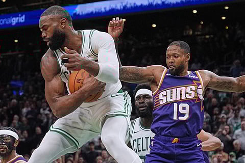 Boston Celtics guard Jaylen Brown, left, grabs a rebound against Phoenix Suns forward Haywood Highsmith during the second half of an NBA basketball game in Boston.