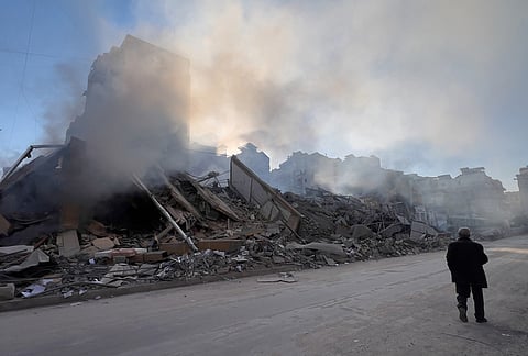 A man passes in front of a destroyed building that housed a branch of Al-Qard Al-Hassan, a non-bank financial institution run by Hezbollah, which was hit by an Israeli airstrike in Dahiyeh, Beirut's southern suburbs, Lebanon, Tuesday, March 10, 2026. 