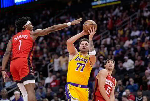 Los Angeles Lakers' Luka Doncic (77) shoots as Houston Rockets' Amen Thompson (1) defends during the first half of an NBA basketball game in Houston.