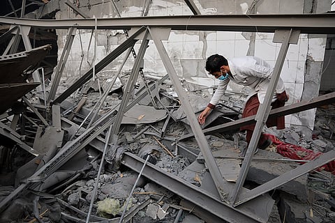 A medical worker reaches toward a body entangled in the rubble of a drug rehabilitation hospital after it was hit by a late-Monday airstrike in Kabul, Afghanistan.