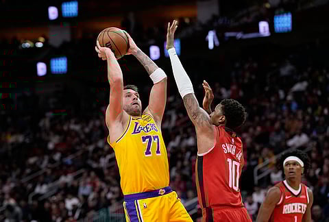 Los Angeles Lakers' Luka Doncic (77) shoots as Houston Rockets' Jabari Smith Jr. (10) defends during the first half of an NBA basketball game in Houston. 