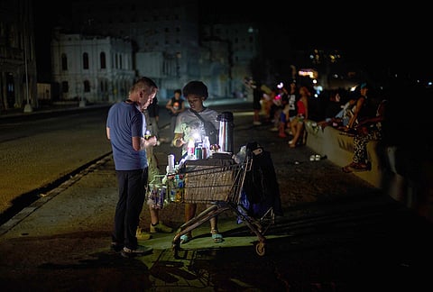 A street vendor tends to a customer on the Malecón during a blackout in Havana, Monday, March 16, 2026. 
