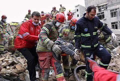 Rescue workers carry a severely injured man after pulling him from the rubble following a strike in southern Tehran, Iran, Friday, March 13, 2026. 