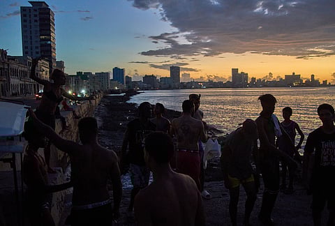 People watch the sunset from the Malecón during a blackout in Havana, Monday, March 16, 2026. 