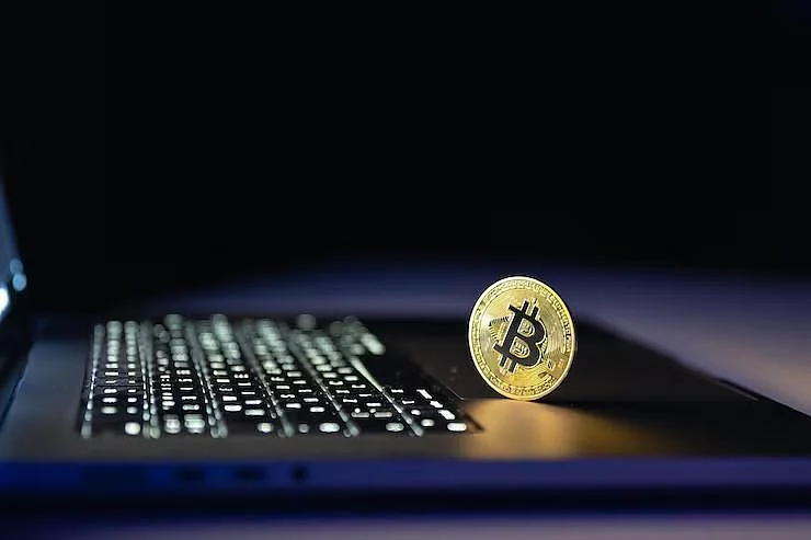 Gold Bitcoin coin on a laptop keyboard
