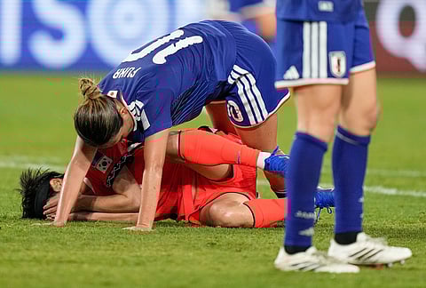 Japan's Fuka Nagano falls over and South Korea's Ji So-yun during the Women's Asian Cup semifinal soccer match between Japan and South Korea in Sydney.