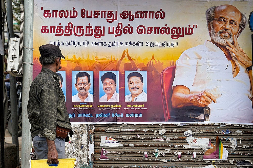 People walk past a wall poster put up by fans of veteran actor Rajinikanth, reflecting his reaction to a recent speech by TVK office-bearer Aadhav Arjuna, in Chennai. - | Photo: PTI/R Senthilkumar